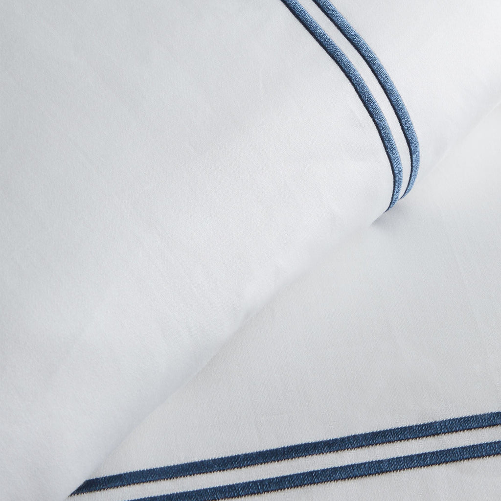 Close-up of white fabric with blue piping on a light gray background