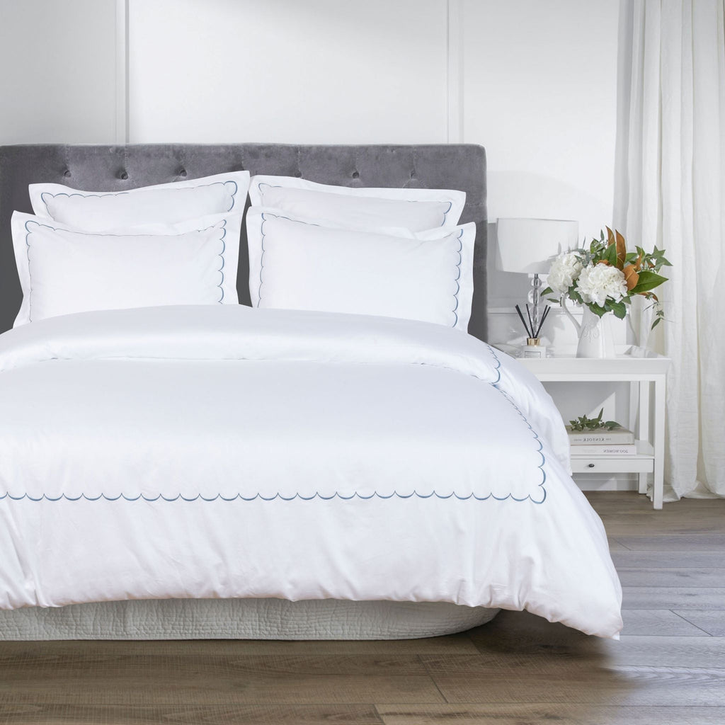 White bedding set on a bed with a gray headboard in a bedroom setting - The Well Appointed House